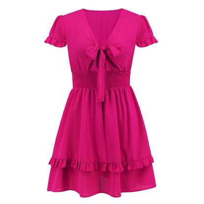 A vibrant ruffled dress featuring a bow-tie neckline, smocked waist, and flared layered hem, styled for a romantic and elegant look