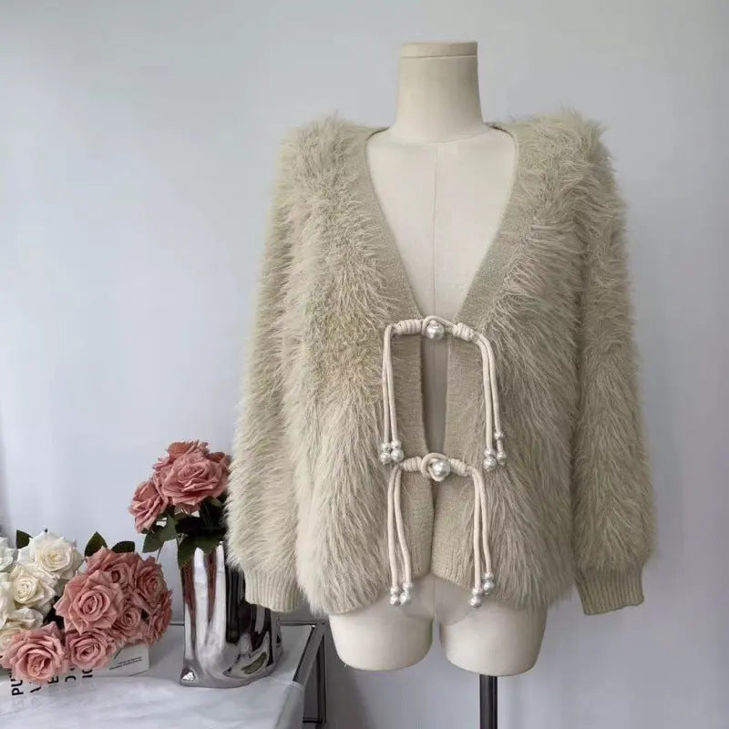 A beige faux fur cardigan with a deep V-neck and traditional Chinese-style toggle closures, displayed on a cream mannequin torso. The cardigan features soft, fluffy texture and ribbed cuffs and hem.
