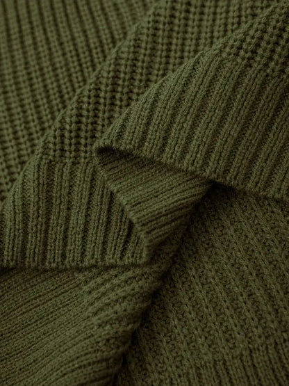 Close-up of olive green ribbed knit fabric with a textured waffle pattern, showing folds and drapery.