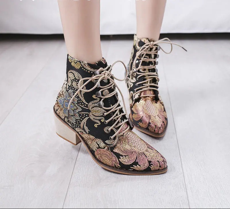 Embroidered boots with floral patterns on a light wooden floor.