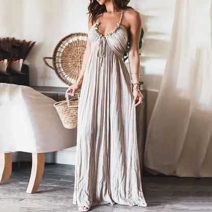 Backless solid-colour maxi dress with U-neckline and thin straps, worn with a woven basket bag in a light-filled interior setting