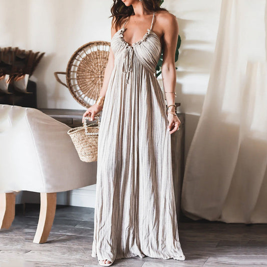 Backless solid-colour maxi dress with U-neckline and thin straps, worn with a woven basket bag in a light-filled interior setting