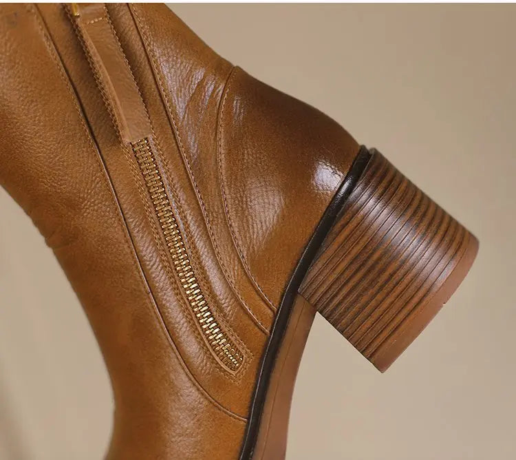 Brown leather boot with a zipper on a beige background