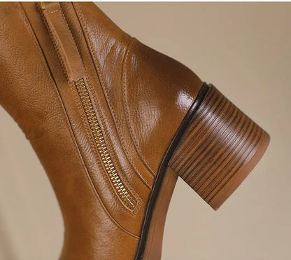 Brown leather boot with a zipper on a beige background