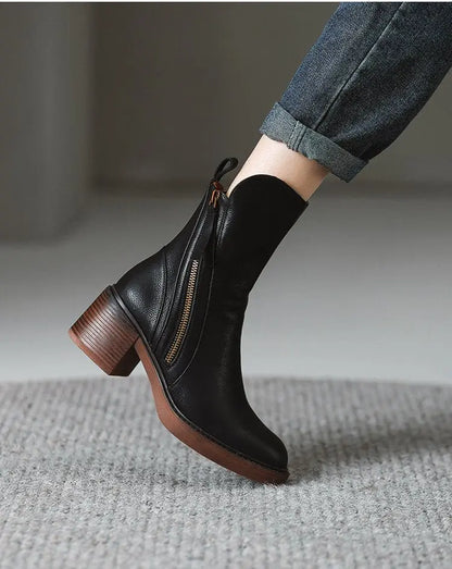 Black ankle boot with brown heel on a neutral background