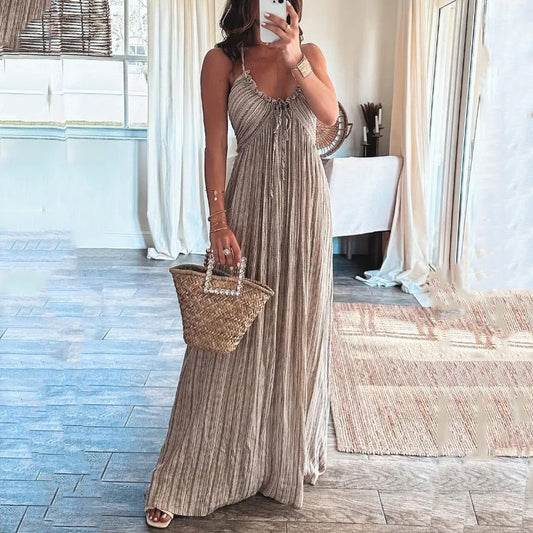 Backless solid-colour maxi dress with U-neckline and thin straps, worn with a woven basket bag in a light-filled interior setting

