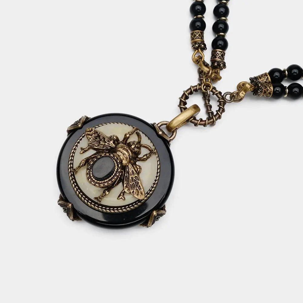 Vintage bee pendant necklace with natural black agate beads and antique copper detailing.