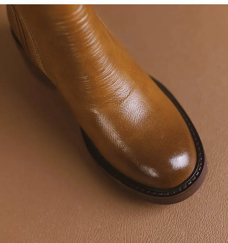 Close-up of a brown leather boot on a matching brown background