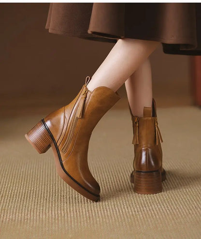 Brown leather boots worn with a brown skirt on a textured surface