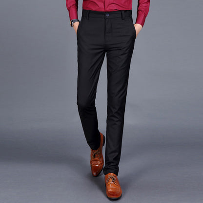 Multiple views of structured tailored trousers in navy, grey, black, and additional colours, styled with a white shirt and brown shoes, highlighting pleats, tapered legs, and buttoned back pockets