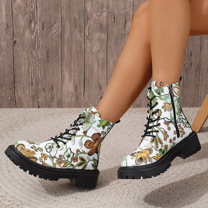 White combat-style boots with a vibrant floral pattern, black laces, deep-tread black soles, and side zippers—bold, stylish, and perfect for any outfit.