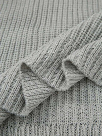 Close-up of a light gray ribbed knit fabric with soft folds showing the texture and weave.