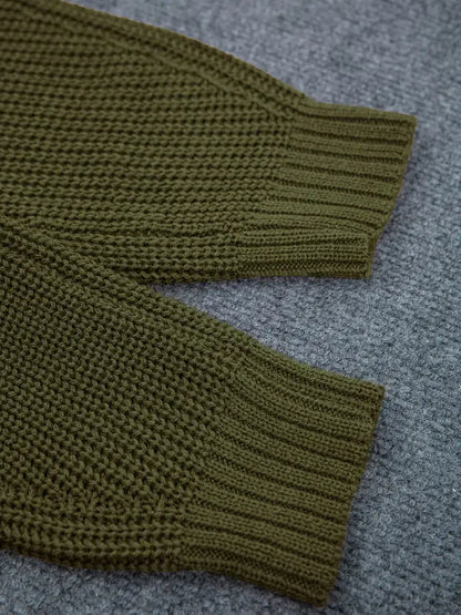 Close-up of olive green ribbed knit fabric, showing the texture and cuff detail, laid flat on a gray textured background.