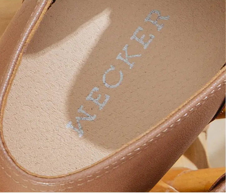 Close-up of the insole of a brown leather shoe, showing the brand name 'WECKER' printed on it, with Chinese text at the top describing the soft, breathable insole.