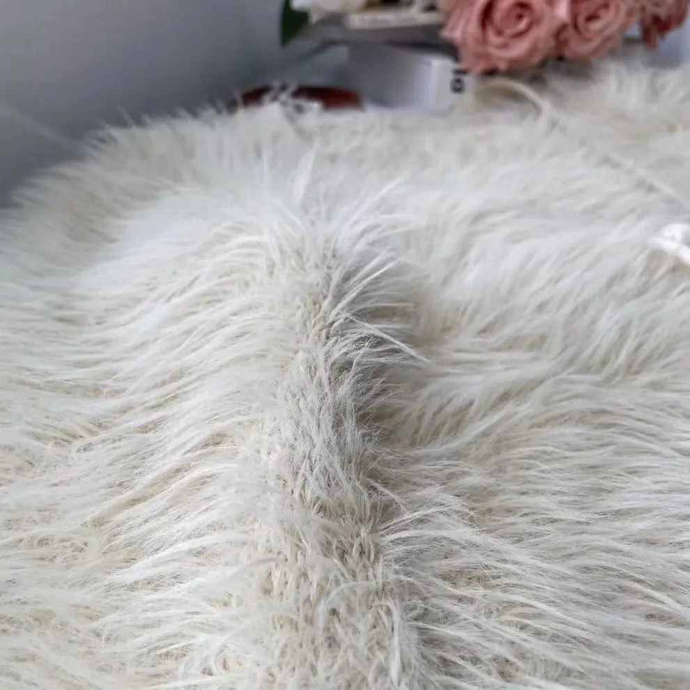 A close-up of a fluffy faux fur throw blanket in off-white, showing the soft, shaggy texture of the material.