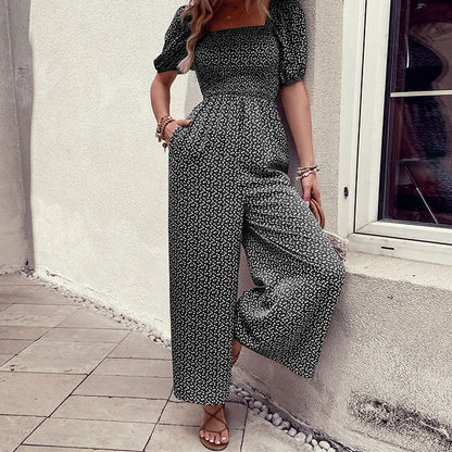Elegant black floral jumpsuit with square neckline, puffed short sleeves, and wide-leg pants – stylish, breathable, and perfect for casual or chic occasions.