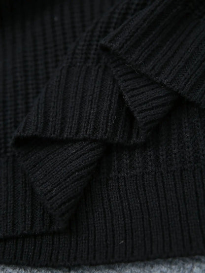 Close-up of a black ribbed knit fabric, showing the detailed texture and folds of the material.