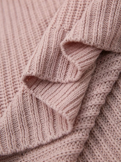 Close-up of a dusty pink ribbed knit fabric with layered draped folds showing the soft texture and stitch detail.