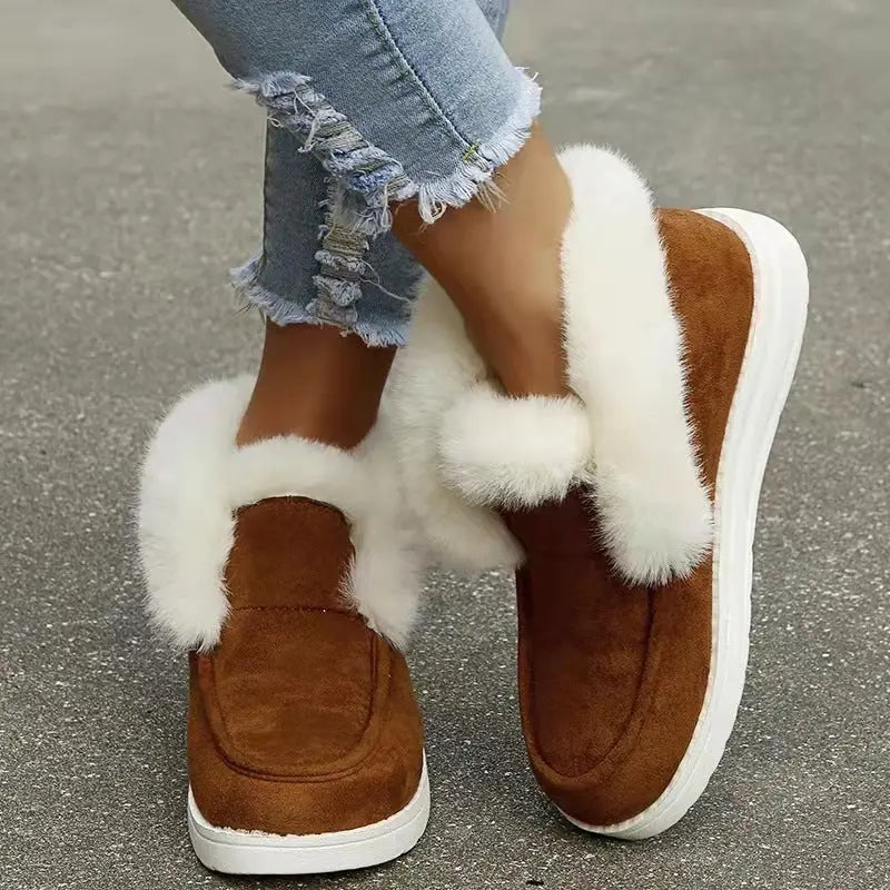 Brown slip-on shoes with white fur lining worn with ripped jeans on a concrete surface.