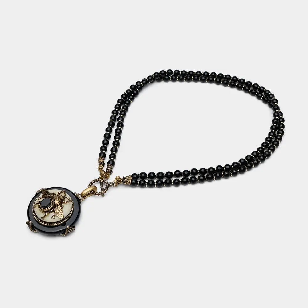 Vintage bee pendant necklace with natural black agate beads and antique copper detailing.