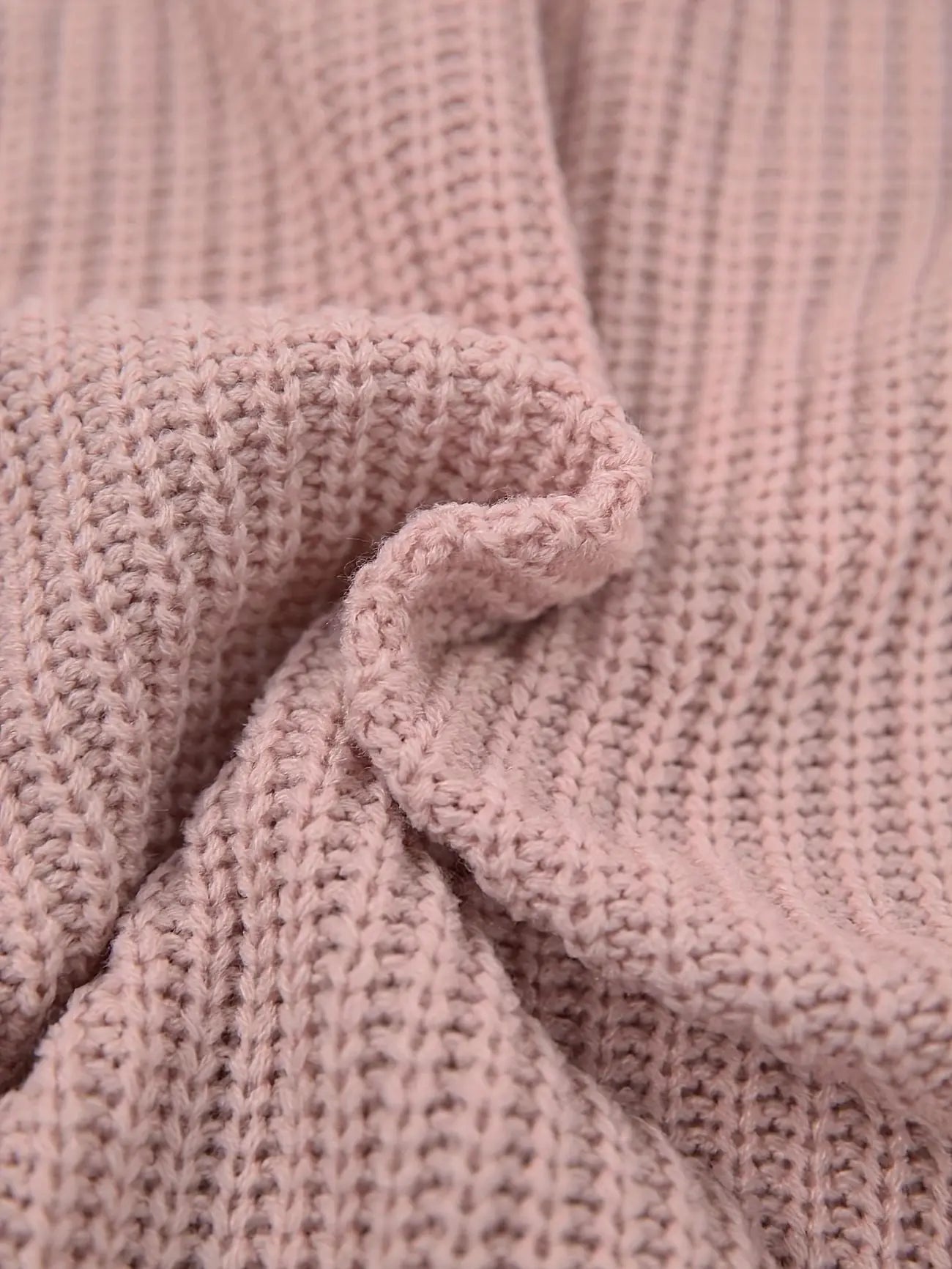 A close-up of a dusty pink ribbed knit fabric, showing the detailed texture and folds of the material.