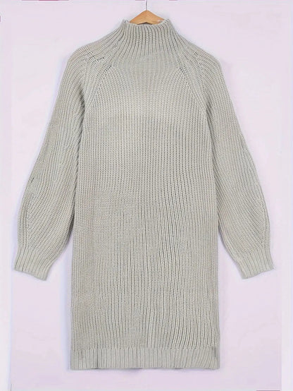 A light sage green ribbed knit mock-neck sweater dress with long raglan sleeves, hanging on a wooden hanger against a pale pink background.