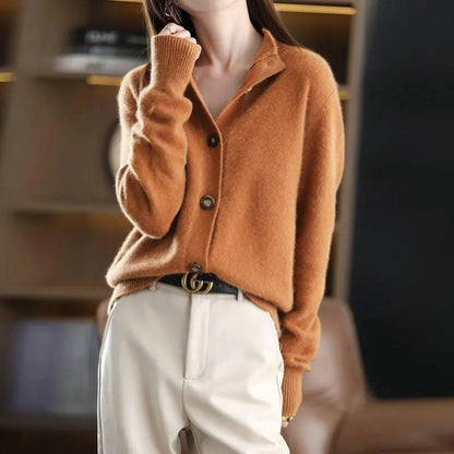 Person wearing a brown sweater and white pants with a blurred background