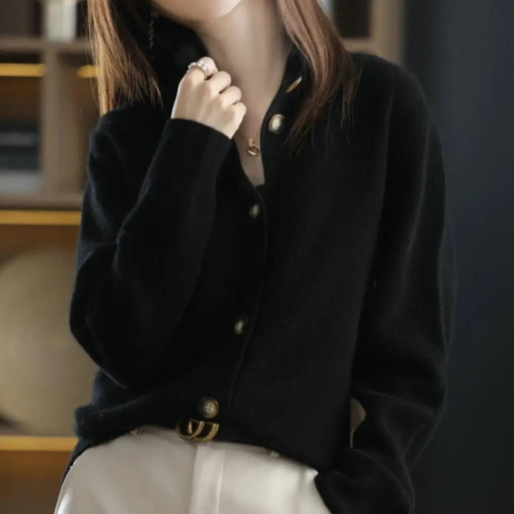 Person wearing a black cardigan with gold buttons in an indoor setting