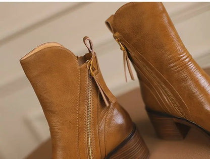 Pair of brown leather boots with zippers on a beige background