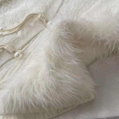 Close-up of a fluffy faux-fur garment in warm off-white/ivory, showing the soft texture and a small pearl-like decorative detail on a drawstring.