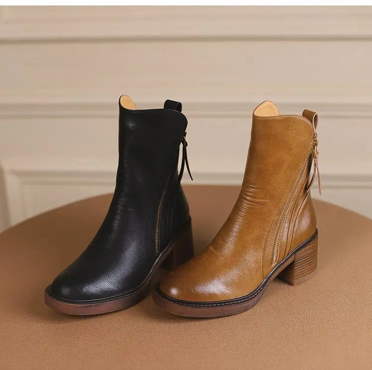 Black and brown leather ankle boots on a beige surface with a neutral background