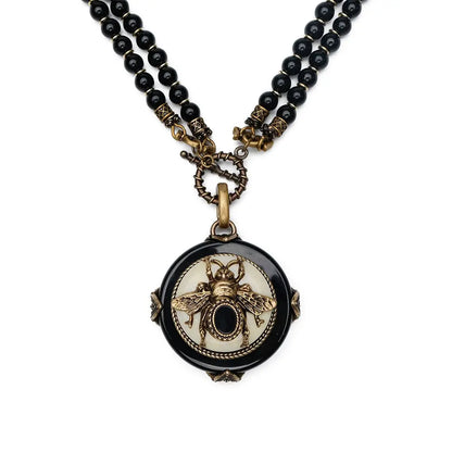 Vintage bee pendant necklace with natural black agate beads and antique copper detailing.