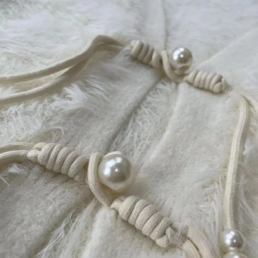 Cream-colored braided cord jewelry with round white faux-pearl beads, displayed on a fluffy white faux fur surface.