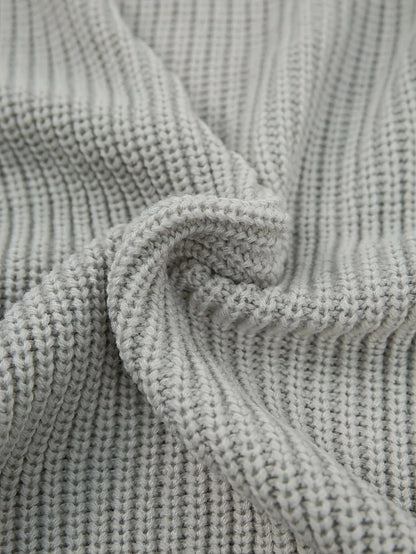 Close-up of a light gray ribbed knit fabric with a soft, draped texture.