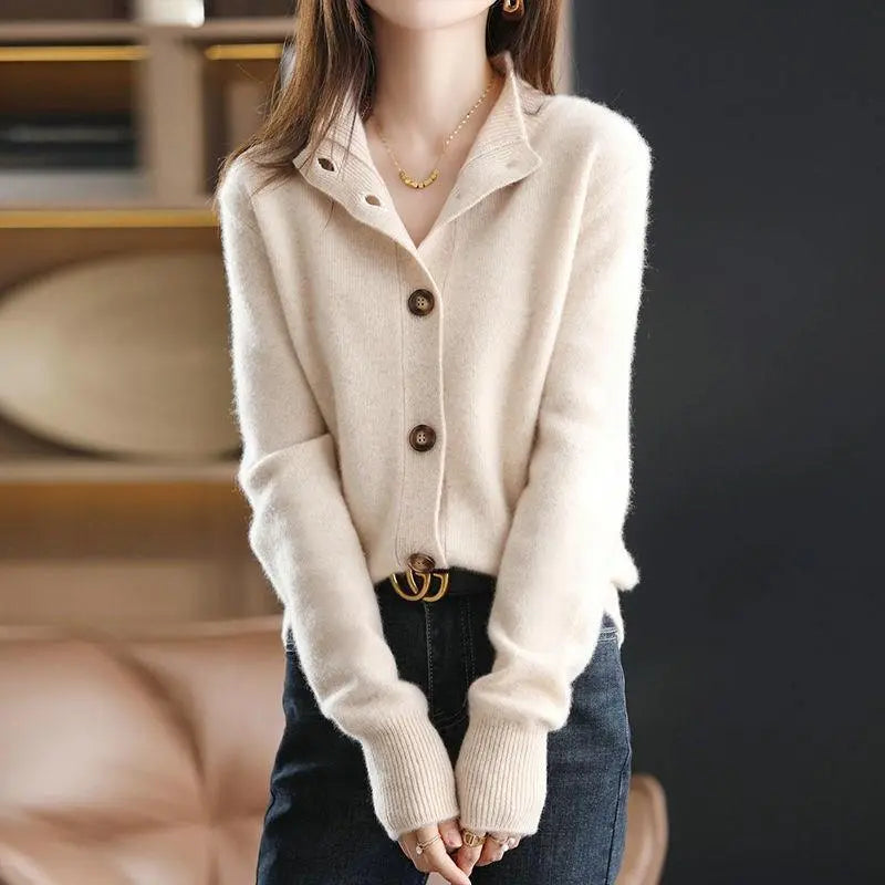 Person wearing a beige button-up sweater with a blurred background