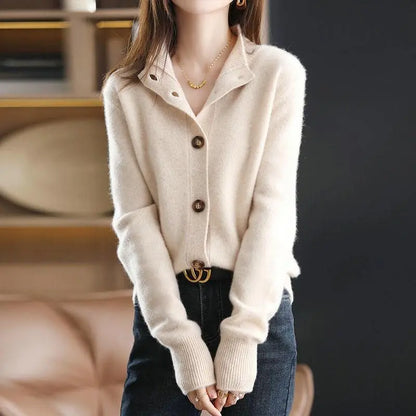 Person wearing a beige button-up sweater with a blurred background