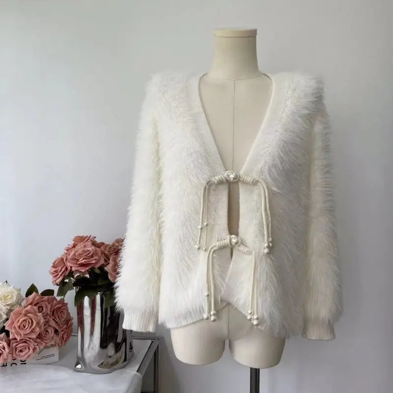 A fluffy off-white faux fur cardigan with a deep V-neck and traditional Chinese-style drawstring closure with pearl beads, displayed on a mannequin torso.