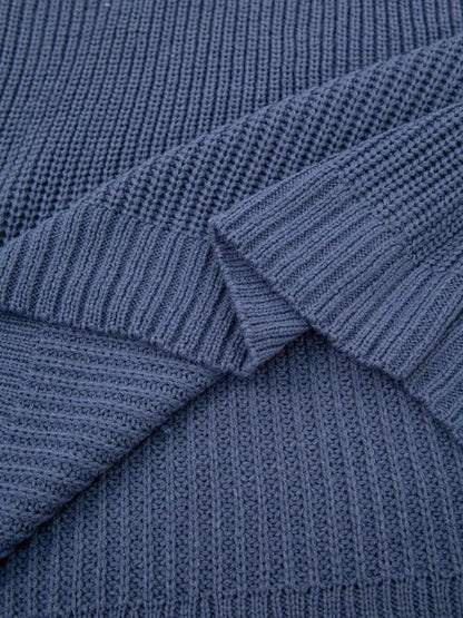 Close-up of a textured knit fabric in a muted slate blue color, showing the ribbed pattern and folded layers.
