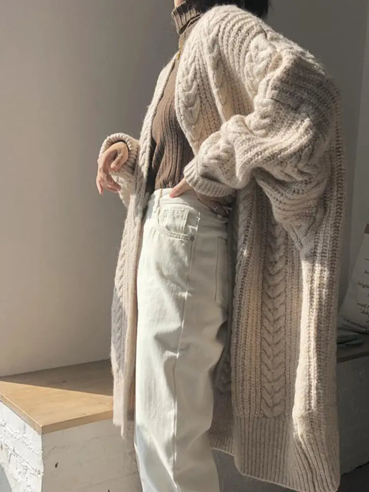 Person wearing a beige knitted cardigan in an indoor setting