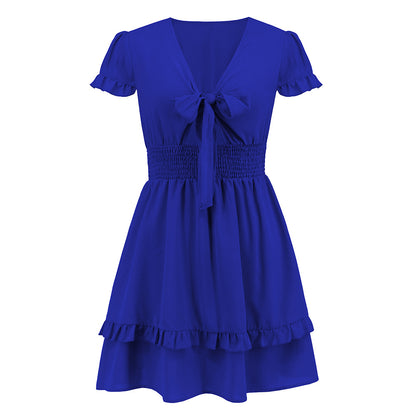 A vibrant ruffled dress featuring a bow-tie neckline, smocked waist, and flared layered hem, styled for a romantic and elegant look