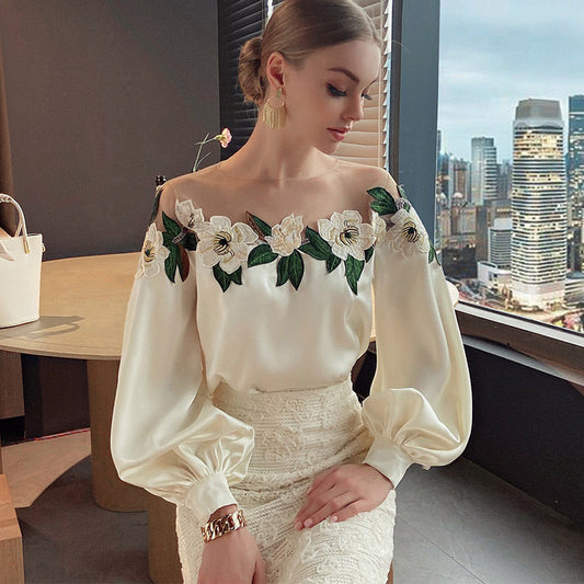 Woman wearing an off-the-shoulder blouse with white floral embroidery and puffed sleeves, paired with a textured high-waist skirt—sophisticated, chic, and perfect for both casual and dressy outfits.