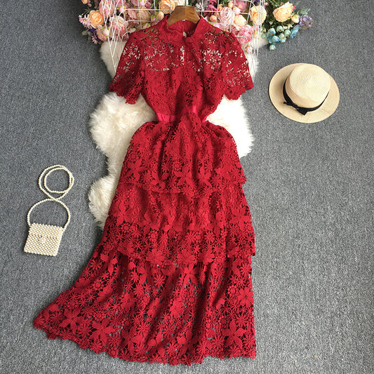 Red lace dress with a straw hat and beaded handbag on a gray surface