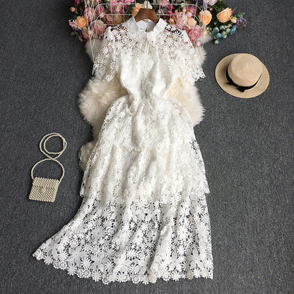 White lace dress with a hat, handbag, and flowers on a dark surface