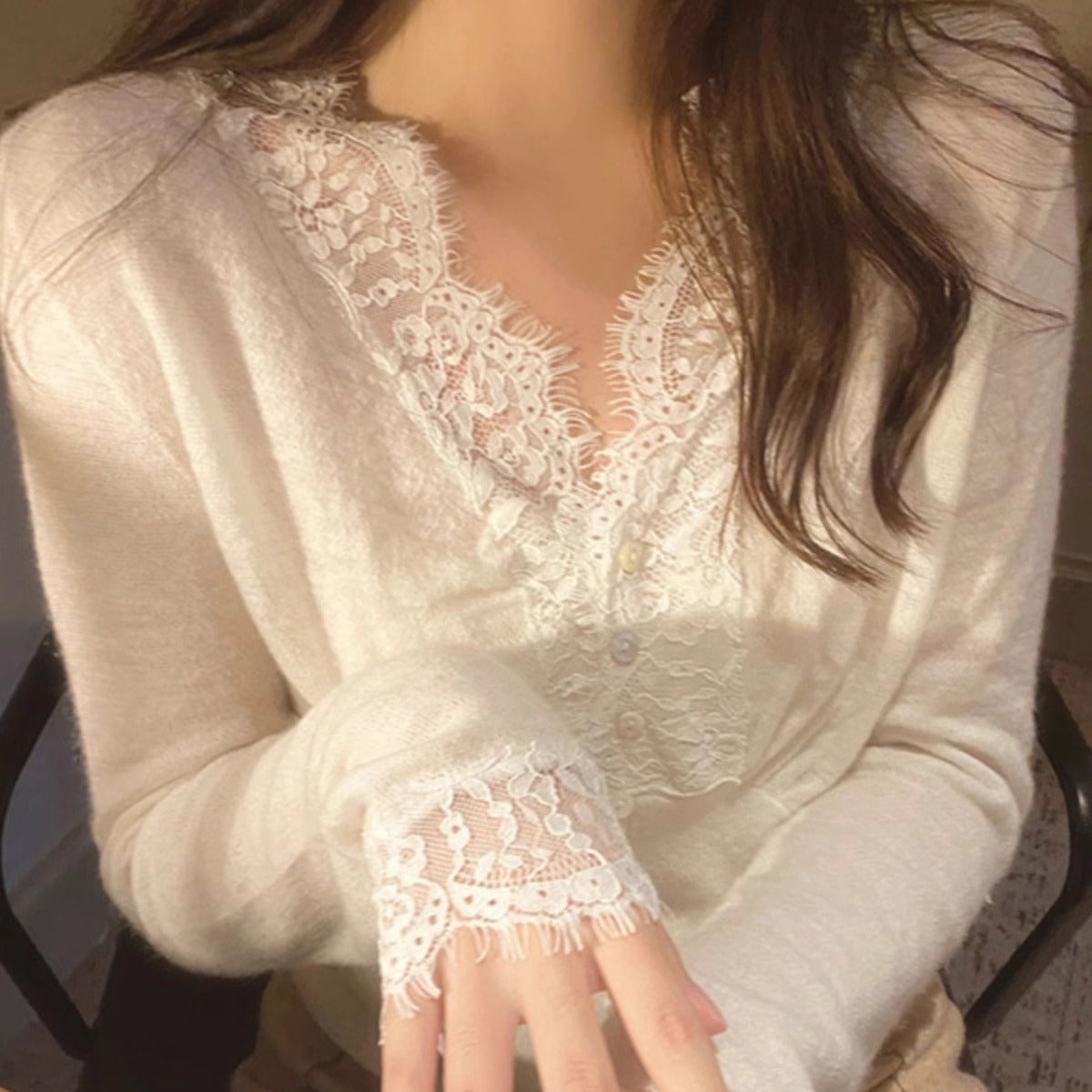 White sweater with intricate floral lace detailing around the neckline and cuffs, styled with delicate accessories—elegant, cozy, and perfect for both casual and dressy outfits.