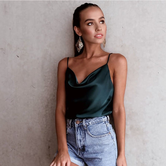 Woman wearing a black satin camisole top, styled with a light blue denim skirt, holding a branch with green leaves—modern, elegant, and perfect for casual or dressy looks.