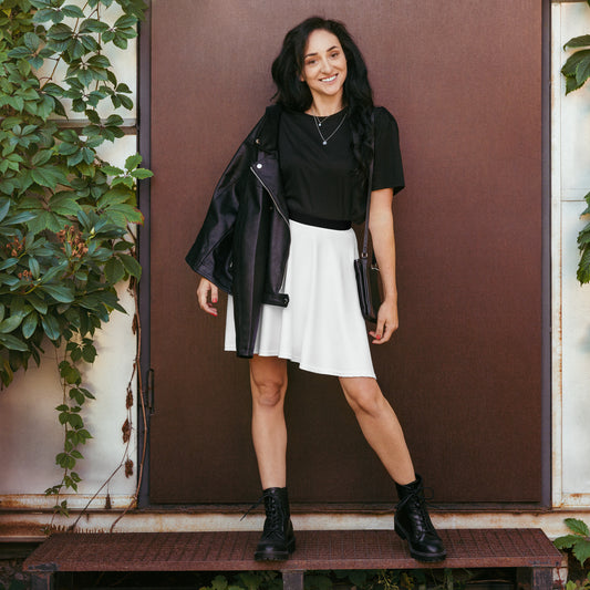 Person wearing a black t-shirt, white skirt, black combat boots, and a black leather jacket draped over one shoulder, holding a small black purse—stylish, versatile, and perfect for chic everyday wear.