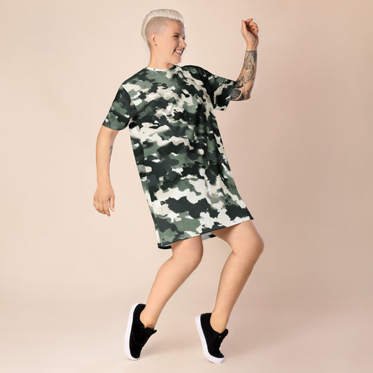 Person wearing a camouflage-patterned t-shirt dress featuring green, black, and white shades, paired with black sneakers with white soles—stylish, sporty, and perfect for casual streetwear.