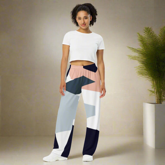 Woman wearing high-waist wide-leg pants with a geometric print in navy, light blue, pink, and white—styled with a beige long-sleeve shirt for an effortlessly chic look.