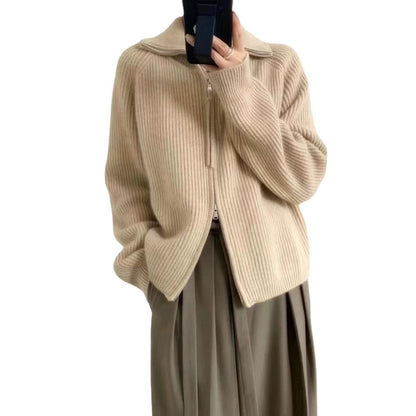 Woman wearing a beige ribbed knit sweater with a high collar and a partially zipped front, styled with light pink pants and delicate accessories—cozy, stylish, and perfect for layering.