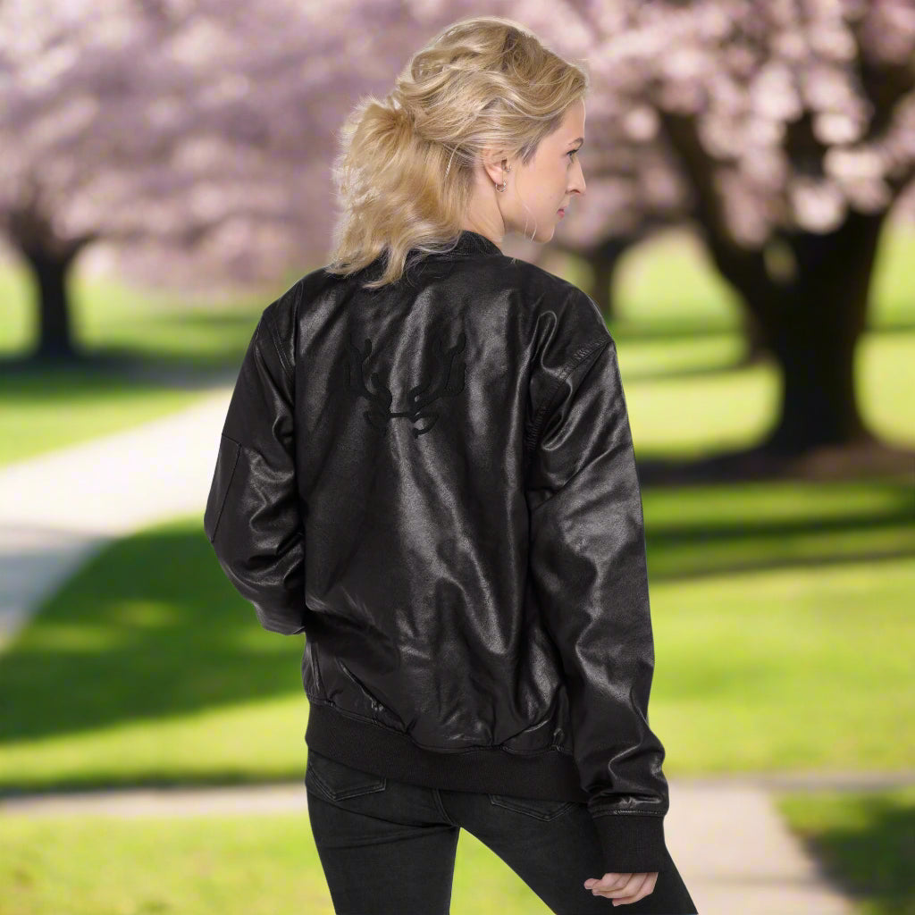 Black faux leather jacket with ribbed cuffs and hem, a zip-up front, soft grey inner lining, and a small embroidered deer logo on the chest—stylish, structured, and perfect for casual or dressy outfits.